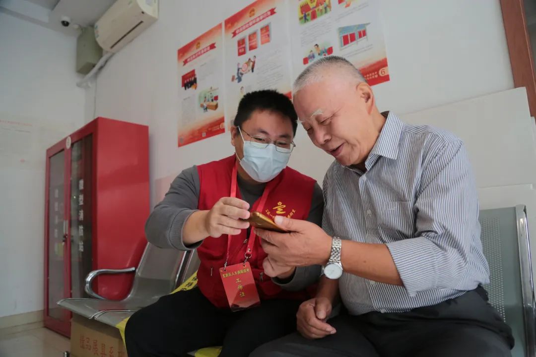 5-10月12日,玄武區(qū)玄武門街道公教一村社區(qū)志愿者教老人手機(jī)登錄“我的南京APP—直通人大”操作系統(tǒng)。肖日東 攝.JPG 圖片